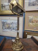 A BRASS TABLE LAMP WITH DIRECTIONAL HALF ROUND SHADE, CYLINDRICAL COLUMN AND STEPPED CIRCULAR