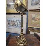 A BRASS TABLE LAMP WITH DIRECTIONAL HALF ROUND SHADE, CYLINDRICAL COLUMN AND STEPPED CIRCULAR