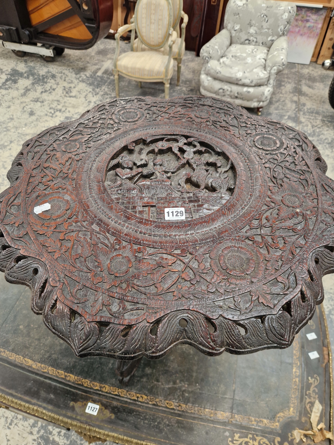 A BURMESE HARD WOOD TABLE CARVED IN RELIEF CENTRALLY WITH TWO FIGURES AND A MYTHICAL BEAST, THE WAVY