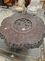 A BURMESE HARD WOOD TABLE CARVED IN RELIEF CENTRALLY WITH TWO FIGURES AND A MYTHICAL BEAST, THE WAVY