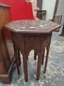 AN ISLAMIC MAHOGANY OCTAGONAL TABLE WITH A GEOMETRIC RELIEF CARVED TOP ABOVE EIGHT LEGS