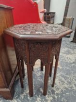 AN ISLAMIC MAHOGANY OCTAGONAL TABLE WITH A GEOMETRIC RELIEF CARVED TOP ABOVE EIGHT LEGS