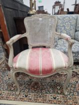 A GREY PAINTED FAUTEUIL WITH A CANED BACK ABOVE THE UPHOLSTERED SEAT ON CABRIOLE FRONT LEGS WITH PEG