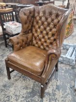 A LEATHER UPHOLSTERED MAHOGANY WING ARMCHAIR, THE ARMS AND BACK BUTTONED AND CLOSE NAILED