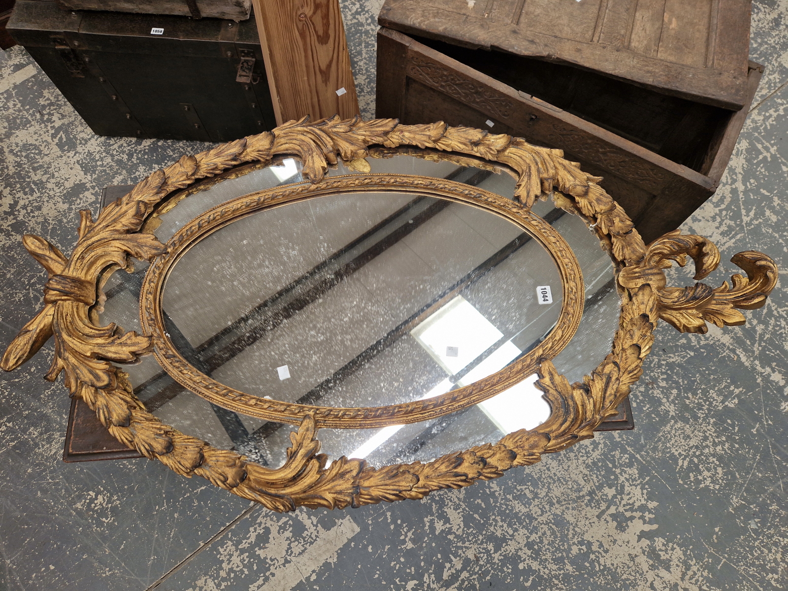 AN OVAL MIRROR WITHIN A FOLIATE GILT FRAME. 130 x 71cms.