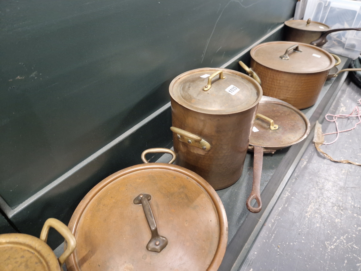 A COLLECTION OF COPPER POTS AND PANS, MOSTLY WITH LIDS