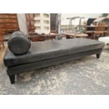 A CONTEMPORARY BLACK UPHOLSTERED CHAISE LONGUE, THE RECTANGULAR SHAPE WITH A CYLINDRICAL CUSHION END