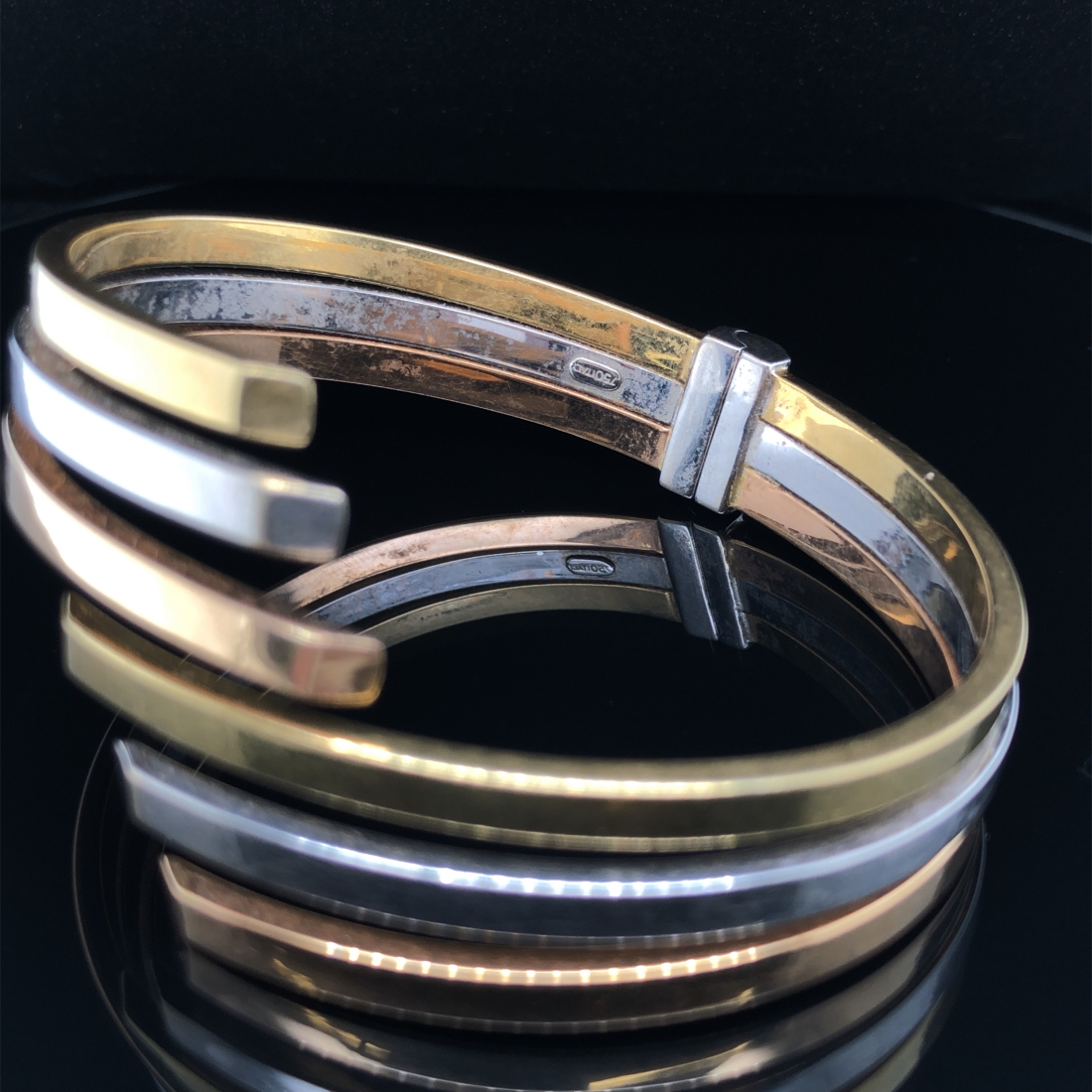 AN ITALIAN THREE COLOUR GOLD SPRUNG HINGED CONTEMPORARY BANGLE. STAMPED 750, ASSESSED AS 18ct - Image 3 of 3