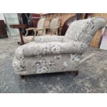 A HOWARD TYPE ARMCHAIR BY WILLIAM BIRCH UPHOLSTERED IN GREY FLORAL MATERIAL, ONE MAHOGANY BACK LEG