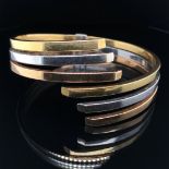 AN ITALIAN THREE COLOUR GOLD SPRUNG HINGED CONTEMPORARY BANGLE. STAMPED 750, ASSESSED AS 18ct