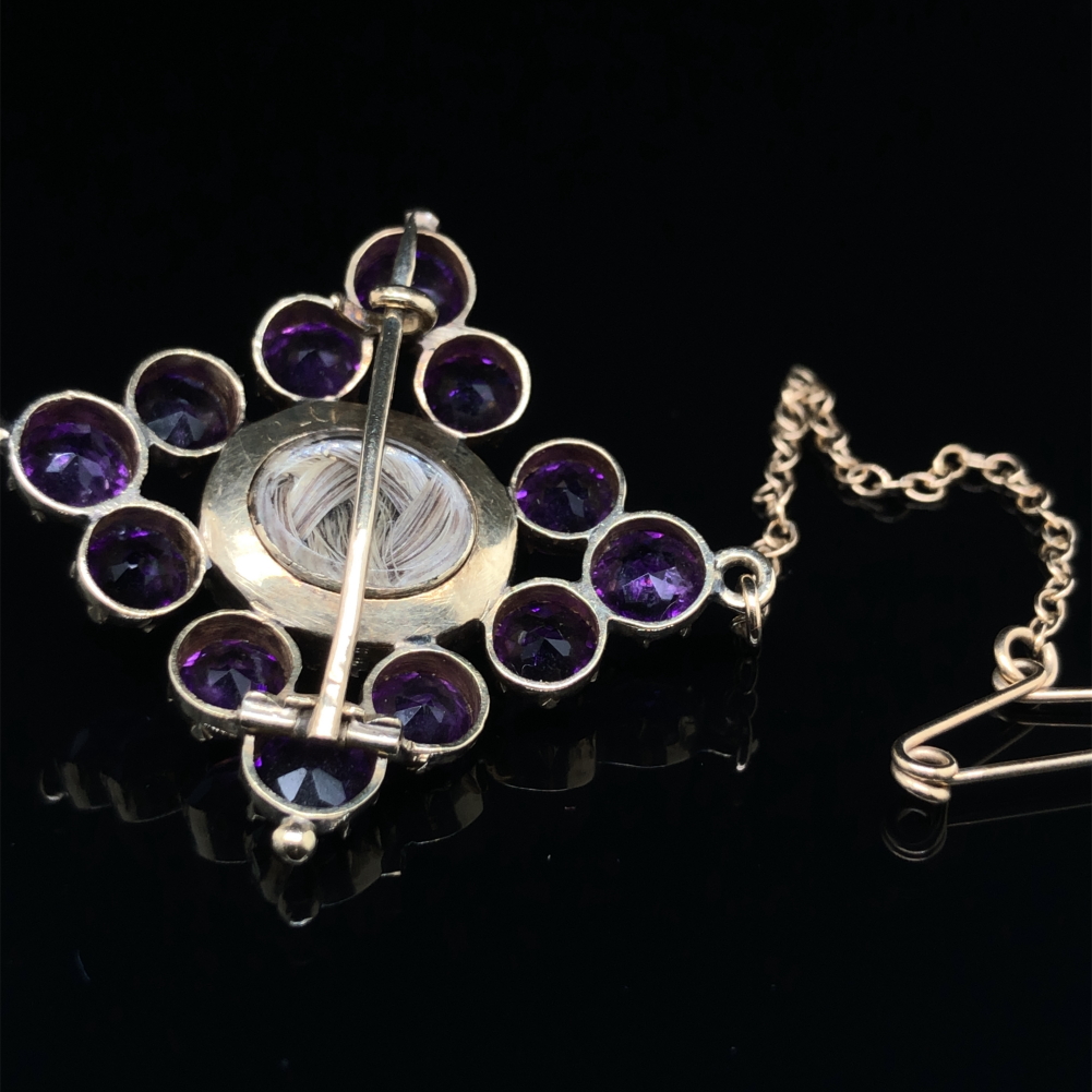 A VICTORIAN MOURNING BROOCH. THE GEMSET AND SEED PEARL BROOCH WITH A GLAZED PANEL TO THE REVERSE