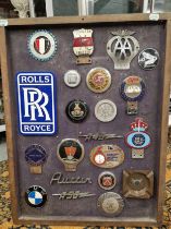 A FRAME OF CAR BADGES, LOGOS AND SOUVENIRS, TO INCLUDE: ROLLS ROYCE, ROVER, RILEY, THE AA AND