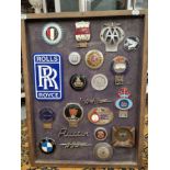 A FRAME OF CAR BADGES, LOGOS AND SOUVENIRS, TO INCLUDE: ROLLS ROYCE, ROVER, RILEY, THE AA AND