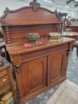 A VICTORIAN MAHOGANY CREDENZA WITH A SHELF BACK ABOVE A DRAWER AND TWO DOORS ON A PLINTH FOOT.   W