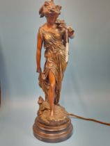 A TABLE LAMP SUPPORTED BY THE SPELTER FIGURE OF A CLASSICAL LADY HOLDING A FLOWERING STEM TO HER