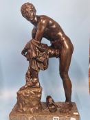 A BRONZE FIGURE OF A ROMAN BATHER WITH ONE FOOT RAISED ON A BLOCK WHILE HE REMOVES A SANDAL, THE