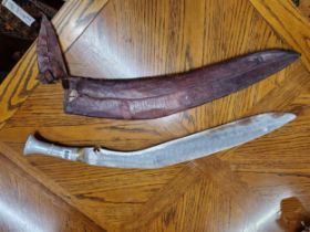 A KUKRI IN A LEATHER SCABBARD, THE HANDLE OF ALUMINIUM, THE OVERALL LENGTH. 73cms.