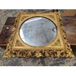 A CIRCULAR MIRROR WITHIN A 19th C. GILT SQUARE FRAME WITH A PIERCED FOLIATE EDGE. 66 x 66cms.