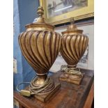 A PAIR OF GILT PLASTER TABLE LAMPS, THE WRYTHEN RIBBED CUP SHAPED BODIES SUPPORTED ON SOCLES AND