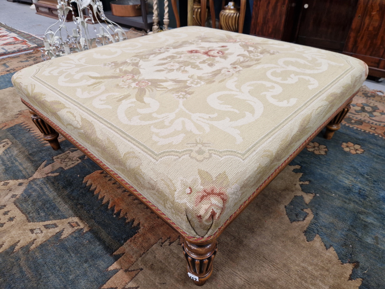 A LATE VICTORIAN STYLE MAHOGANY OTTOMAN, THE SQUARE FLORAL NEEDLE WORKED SEAT ON REEDED CYLINDRICAL