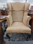 AN ANTIQUE MAHOGANY WING BACK ARMCHAIR, THE CABRIOLE FRONT LEGS ON PAW FEET