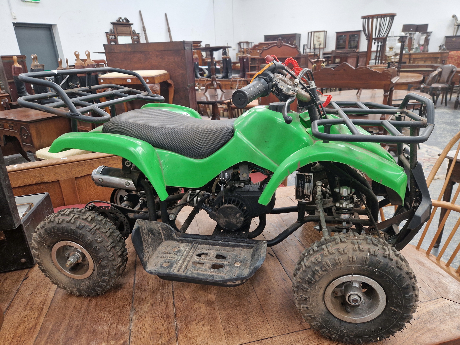 A CHILDS GREEN PLASTIC FOUR WHEELED VEHICLE WITH A LIVE ENGINE USING OIL AND PETROL MIXTURE FUEL