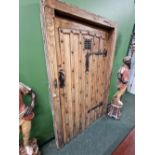 AN ANTIQUE RUSTIC STYLE OAK DOOR WITH IRON STUD WORK AND FITTINGS.