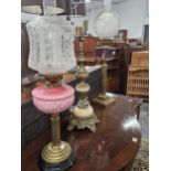 TWO OIL LAMPS WITH COLOURED GLASS RECEIVERS ON REEDED BRASS COLUMNS AND TOGETHER WITH A MARBLE AND
