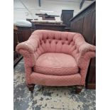 A TUB ARMCHAIR WITH A ROUNDED BUTTON UPHOLSTERED BACK, THE TURNED MAHOGANY FRONT LEGS ON BRASS