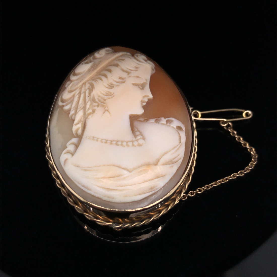 A PORTRAIT CAMEO BROOCH, WITHIN A 9ct STAMPED ROPE EDGE BROOCH FRAME, COMPLETE WITH SAFETY CHAIN.