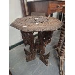 AN ISLAMIC OCTAGONAL TABLE, THE TOP PIERCED AND CARVED WITH A PEACOCK ROUNDEL, THE THREE BUTTRESS