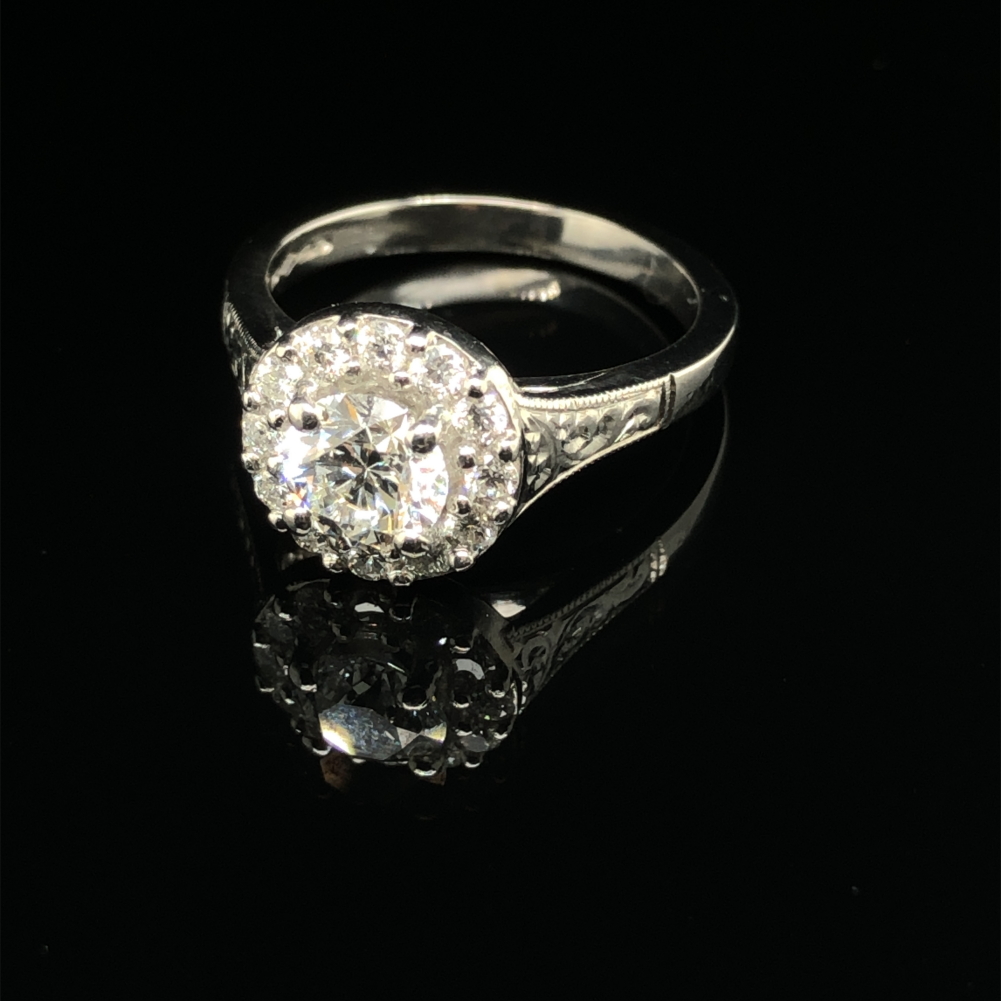A GIA ROUND BRILLIANT CUT DIAMOND AND PLATINUM RING. THE CENTRE DIAMOND 0.71cts, SURROUNDED BY A