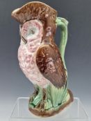 ATTRIBUTED TO GEORGE MORLEY & CO, A MAJOLICA OWL FORM JUG WITH A PINK FLOWER THUMBPIECE TO THE