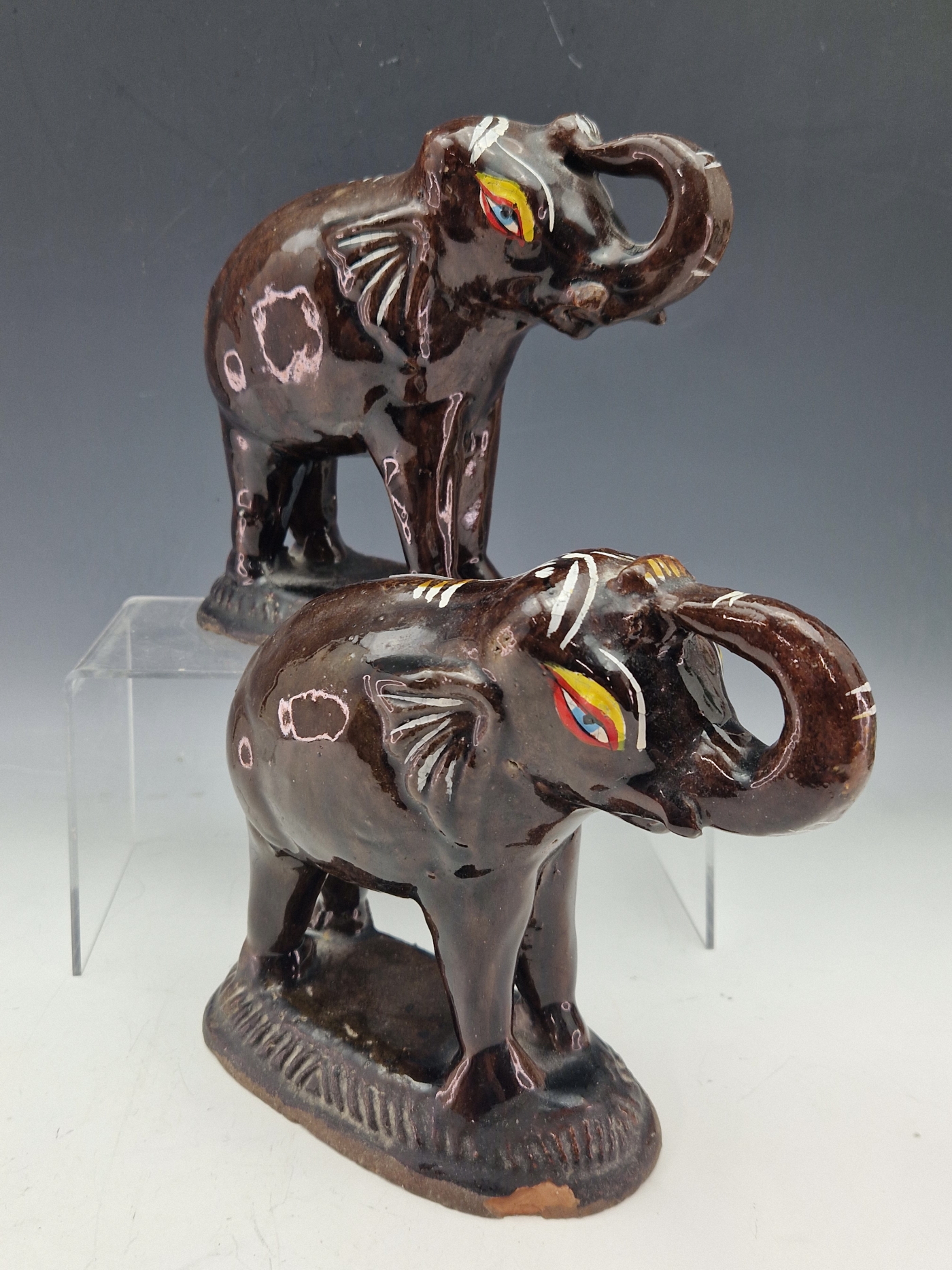 A PAIR OF TREACLE GLAZED ELEPHANT FIGURINES STANDING ON GADROON EDGED PLINTHS WITH THEIR TRUNKS - Image 2 of 3