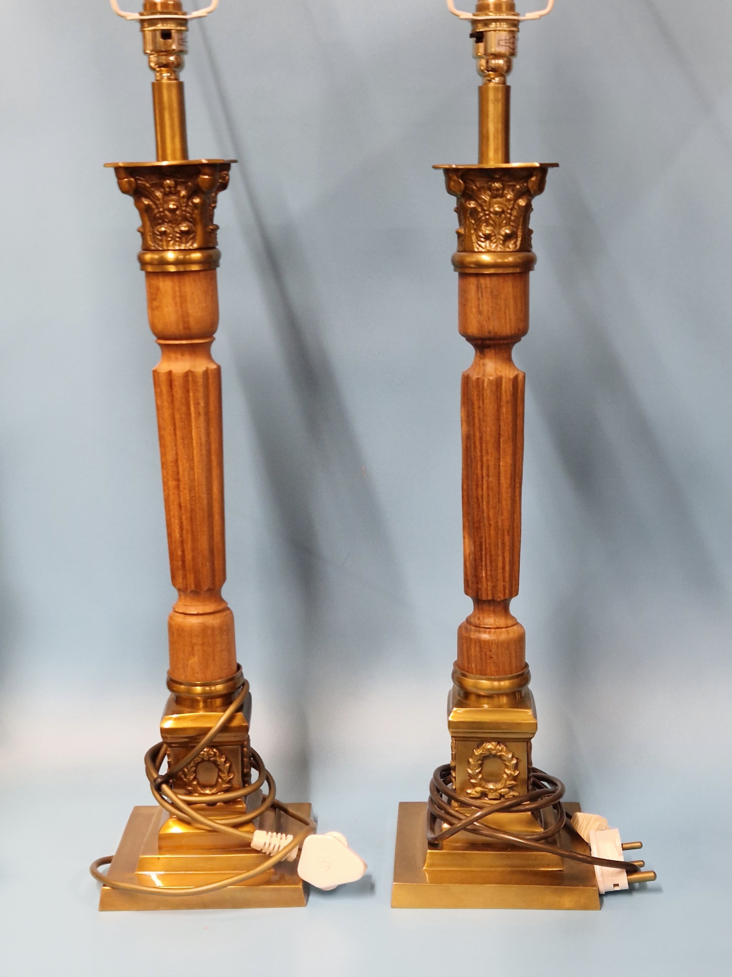 A PAIR OF WOOD AND BRASS CORINTHIAN COLUMN TABLE LAMPS SUPPORTED ON SQUARE FEET. H 63cms