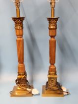 A PAIR OF WOOD AND BRASS CORINTHIAN COLUMN TABLE LAMPS SUPPORTED ON SQUARE FEET. H 63cms