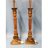 A PAIR OF WOOD AND BRASS CORINTHIAN COLUMN TABLE LAMPS SUPPORTED ON SQUARE FEET. H 63cms