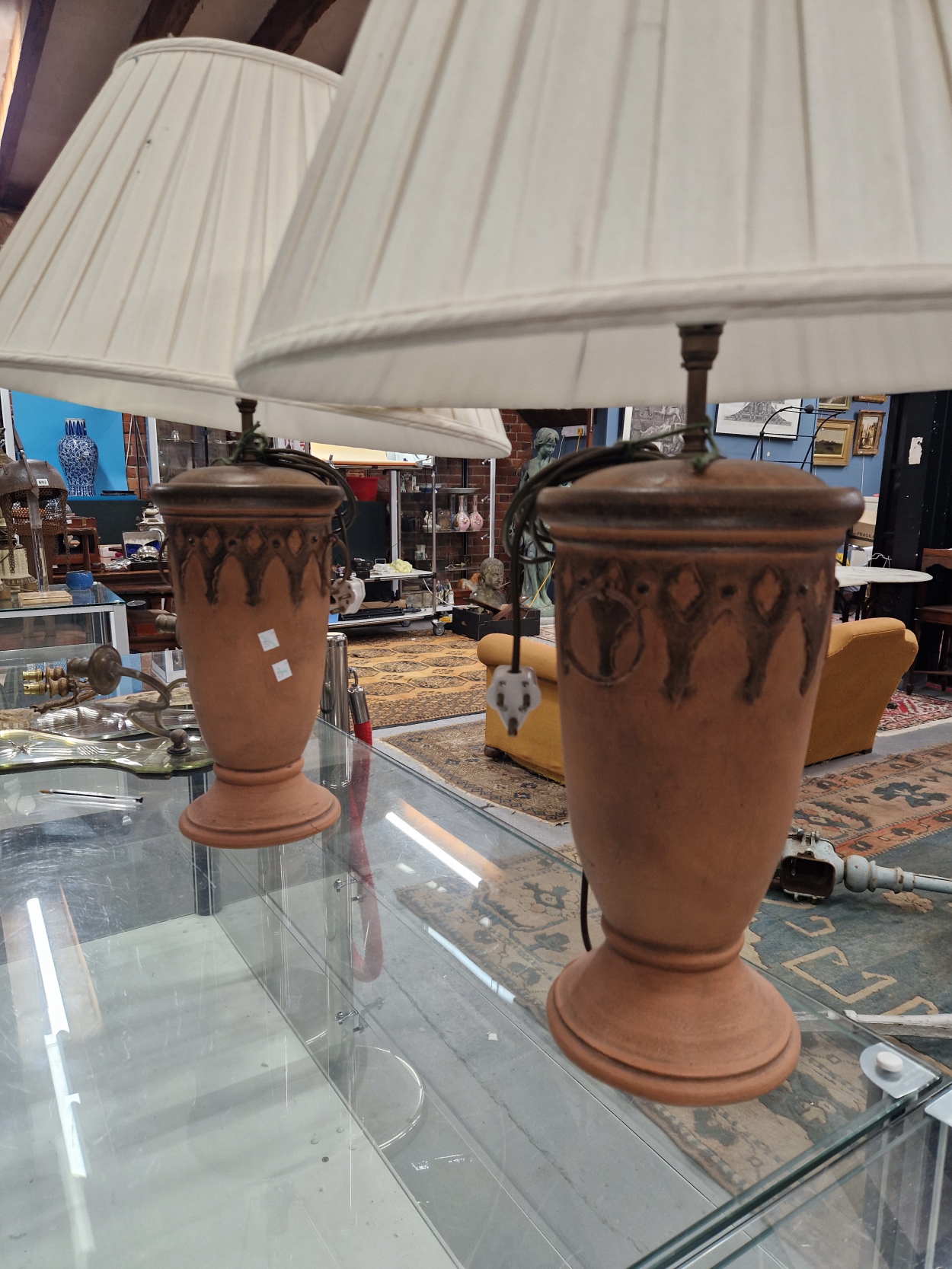 A PAIR OF TERRACOTTA TABLE LAMPS, THE SLENDER OVOID SHAPES RAISED ON CIRCULAR FEET, TO THE TOP OF