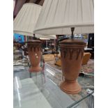 A PAIR OF TERRACOTTA TABLE LAMPS, THE SLENDER OVOID SHAPES RAISED ON CIRCULAR FEET, TO THE TOP OF