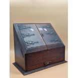 A COPPER MOUNTED OAK STATIONARY BOX, THE CENTRALLY SPLIT SLOPING DOORS ABOVE A SHALLOW DRAWER. W