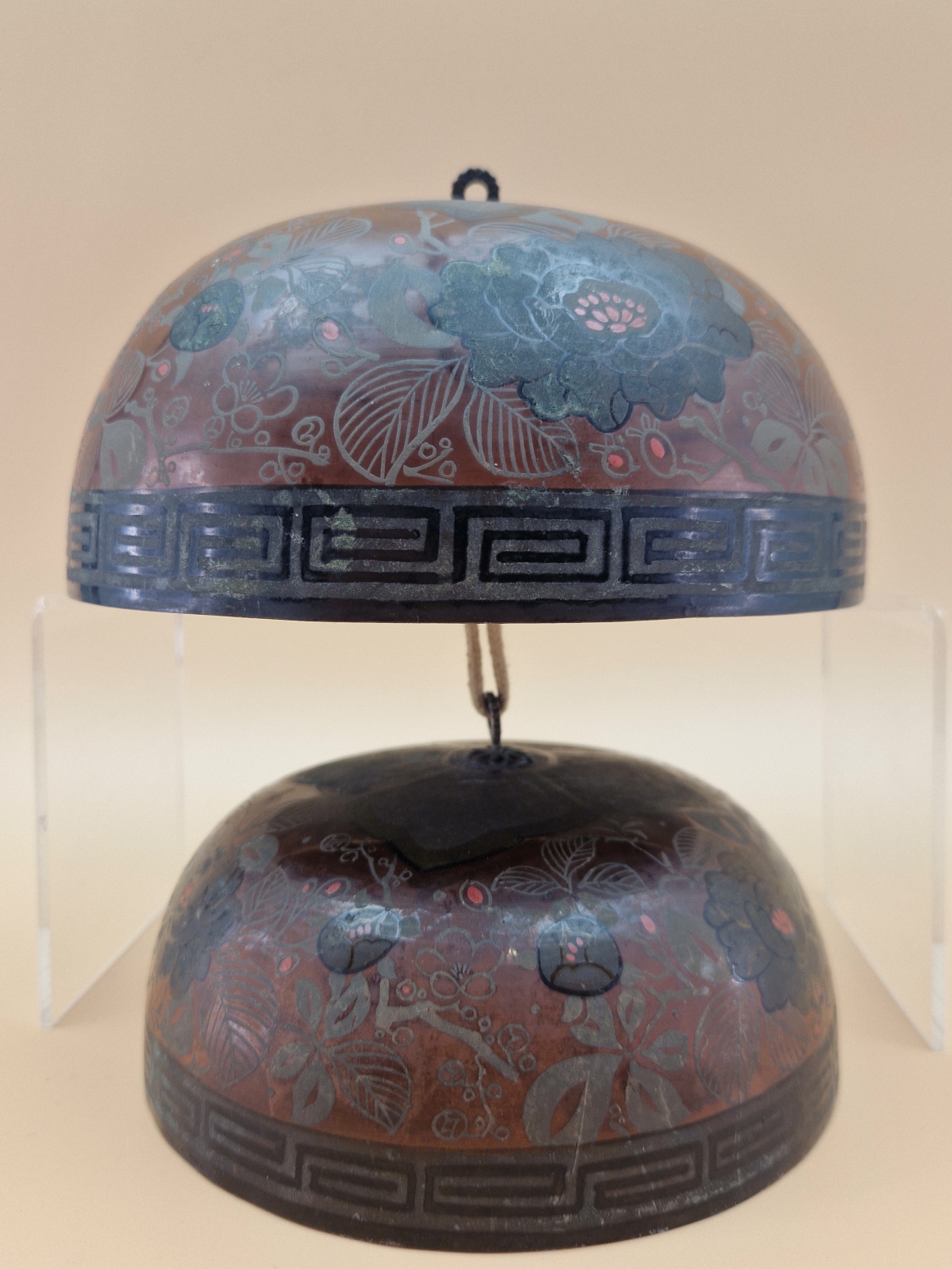 A GRADED SET OF TWO CHINESE SINGING BOWLS DECORATED WITH PEONIES ON A RED GROUND, THE SUSPENSION