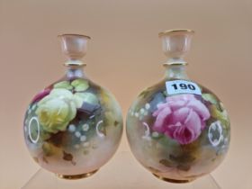 A PAIR OF 1911 ROYAL WORCESTER VASES, THE COMPRESSED SPHERICAL BODIES PAINTED WITH ROSES. H 15.5cms.