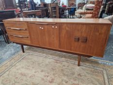 A 1970S TEAK SIDEBOARD, THE CENTRAL PULL DOWN DOOR FLANKED BY THREE DRAWERS AND BY TWO DOORS ABOVE