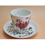 A BOW PORCELAIN COFFEE CUP AND SAUCER PAINTED WITH FLOWERS GROWING BY ROCKS