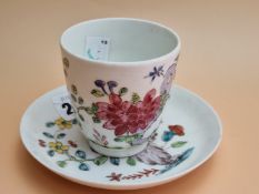 A BOW PORCELAIN COFFEE CUP AND SAUCER PAINTED WITH FLOWERS GROWING BY ROCKS