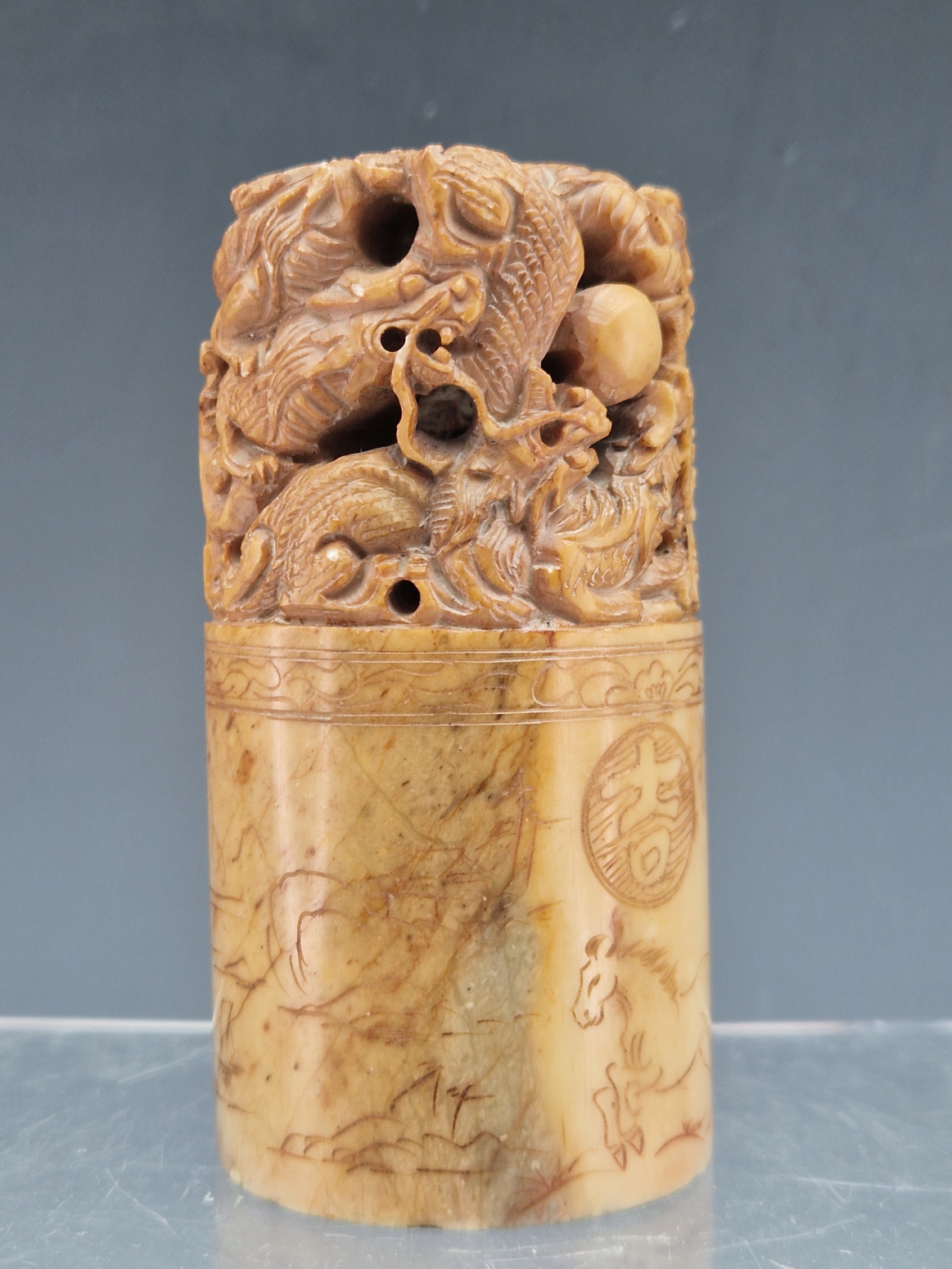 A CHINESE PINK/BROWN SOAPSTONE CYLINDRICAL SEAL PIERCED AND CARVED WITH DRAGONS CHASING A PRECIOUS