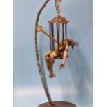 FELIPE GONZALEZ, A CONTEMPORARY BRONZE SCULPTURE OF A MAN IN A CAGE HELD ON A BRACKET ARM RESTING ON