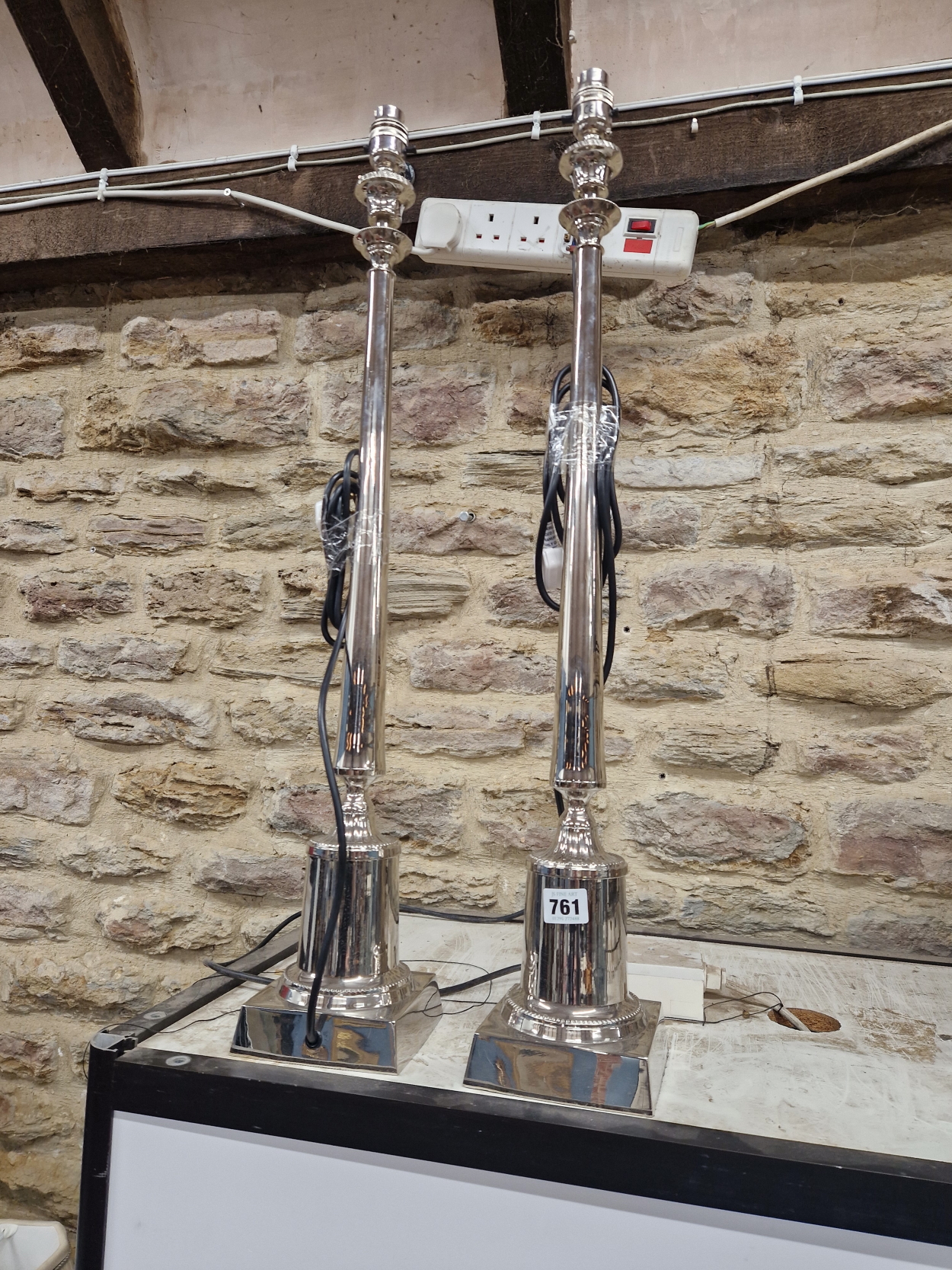 A PAIR OF CHROMED CANDLESTICK COLUMN TABLE LAMPS SUPPORTED ON SQUARE FEET. H 74cms/.