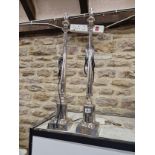 A PAIR OF CHROMED CANDLESTICK COLUMN TABLE LAMPS SUPPORTED ON SQUARE FEET. H 74cms/.