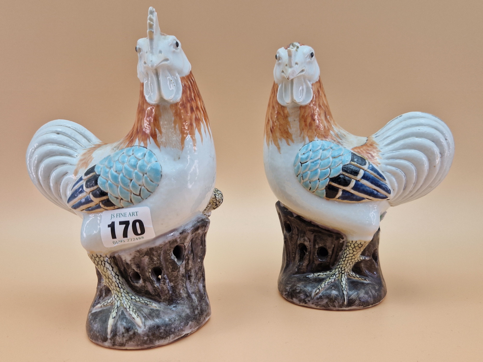 A PAIR OF CHINESE COCKERELS STANDING ON AUBERGINE PAINTED ROCKS. H 19cms.